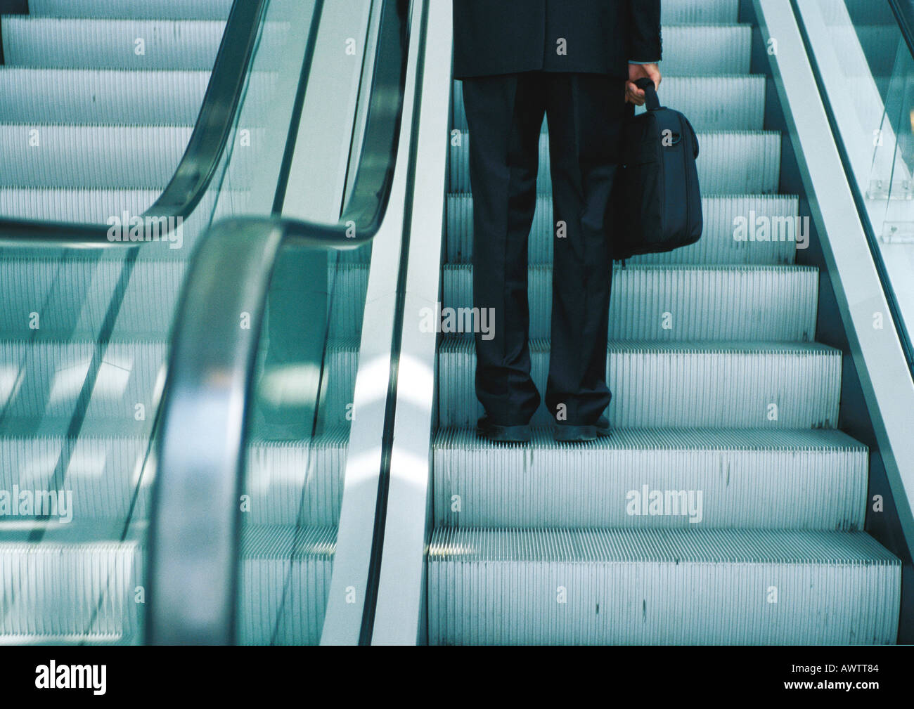 Businessman on escalator, lower section Stock Photo