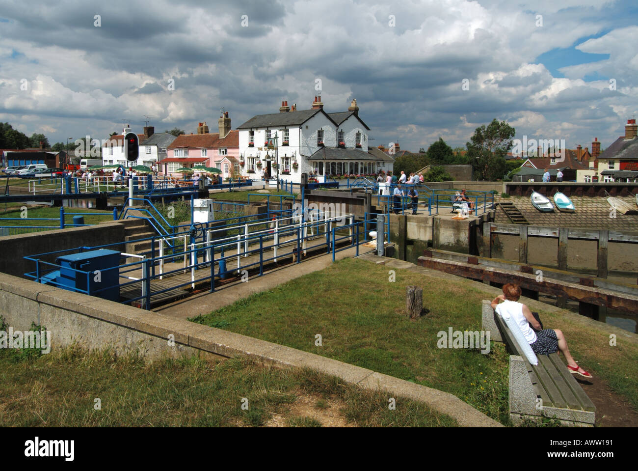 Heybridge Basin people around lock gates where canal section of River Blackwater joins the tidal estuary The Old Ship Inn beyond Essex England UK Stock Photo