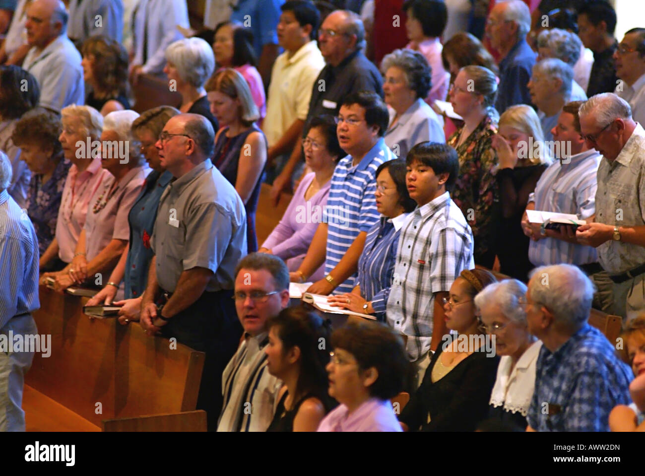 Filipino family sings during Catholic Mass among fellow multi ethnic parishioners Stock Photo
