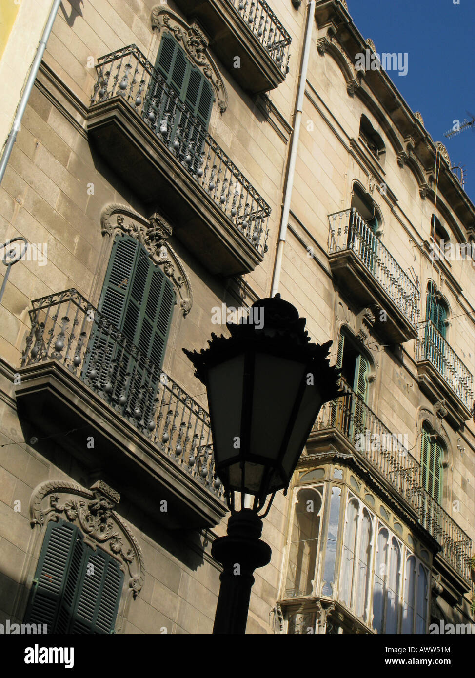 Decorative street lamp silhouette, against a background of ornate iron balconies and an enclosed window balcony. Apartment block Palma, Mallorca Spain Stock Photo