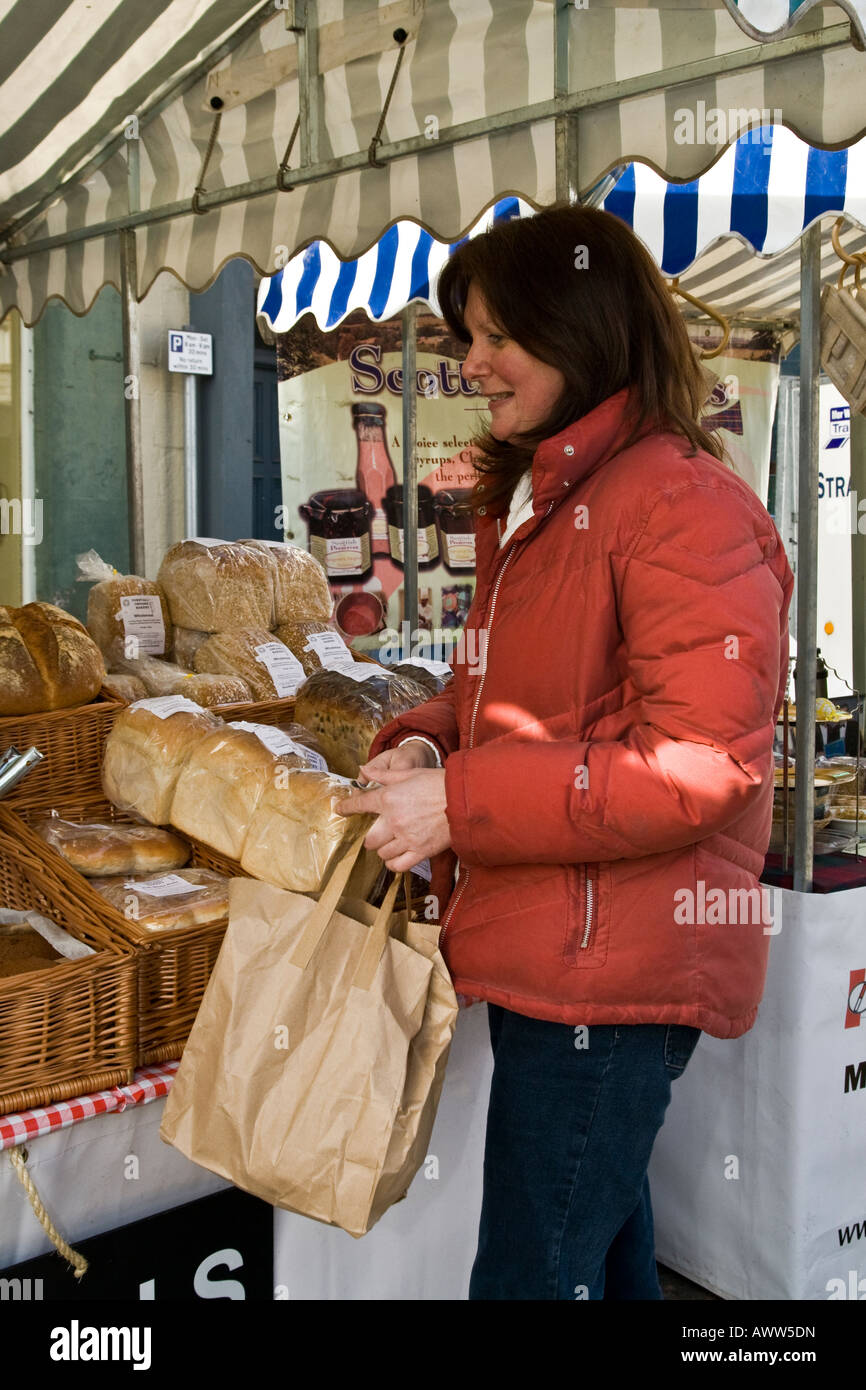 Woman buying homemade freshly baked crusty bread at a local street market in Coupar Angus, UK Stock Photo