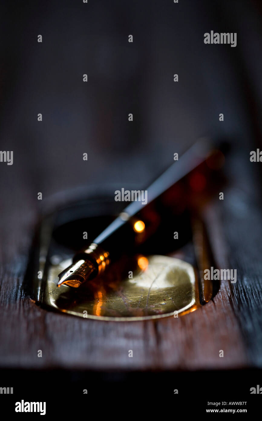 Old wooden school desk with a ink well and fountain pen lit by