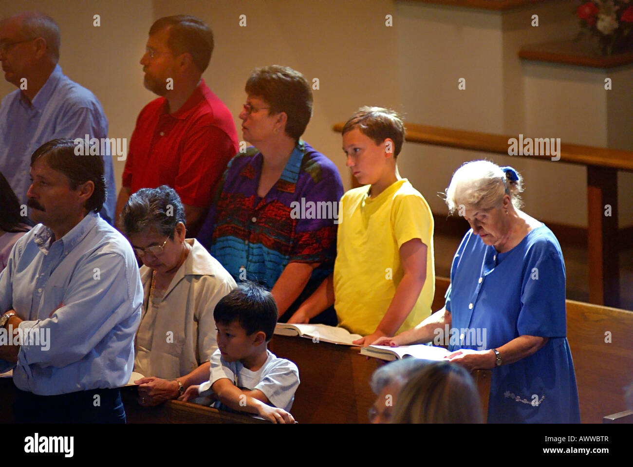 White pre teen boy prays with parents and grandmother during Catholic Mass Stock Photo