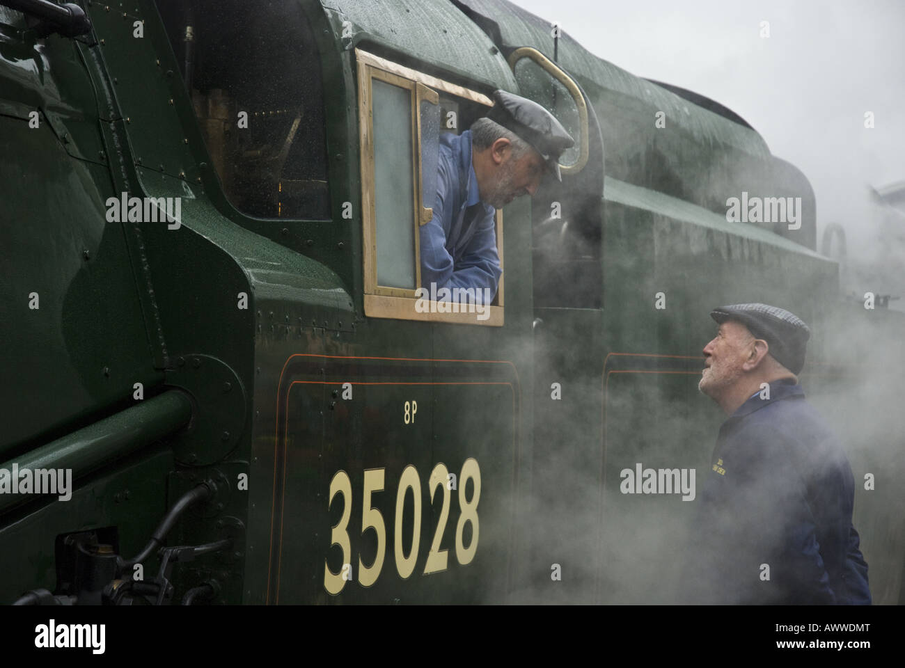 An onlooker talks with the engineer of the Orient Express steam train at London's Victoria Station, UK. Stock Photo