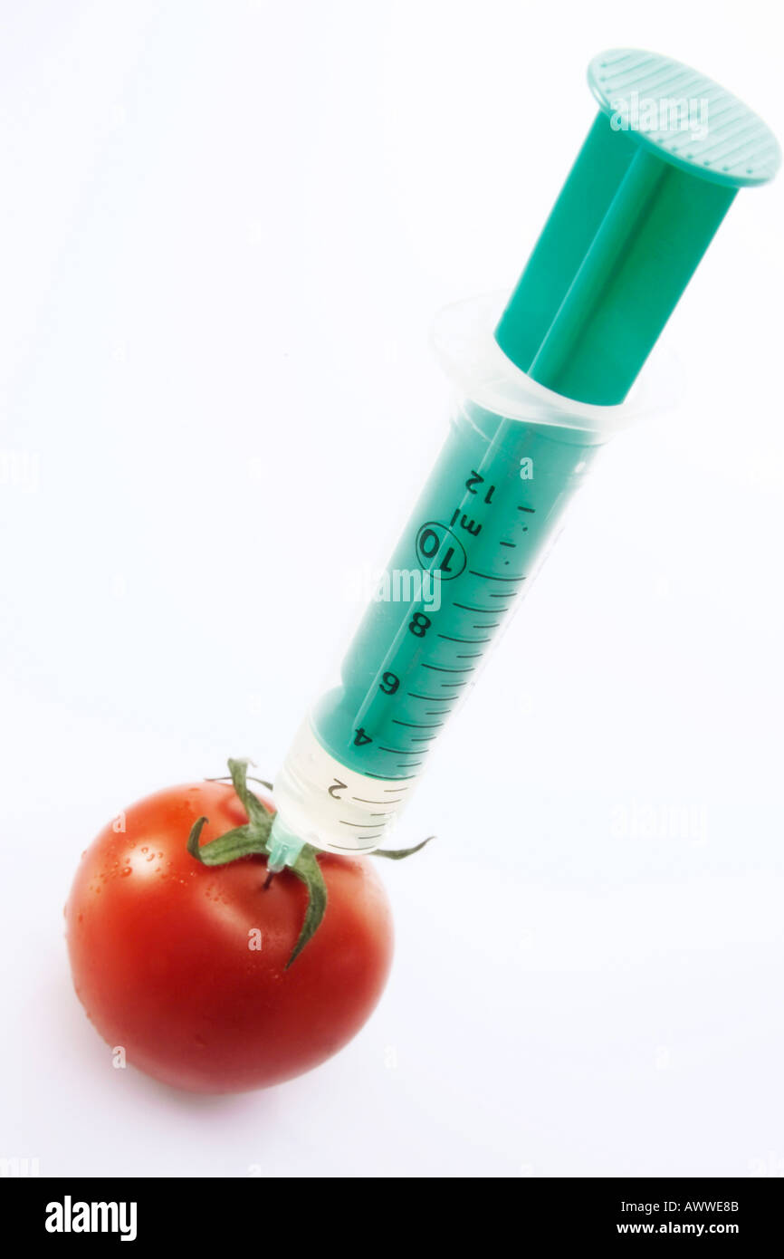 Syringe injecting tomato, close-up Stock Photo