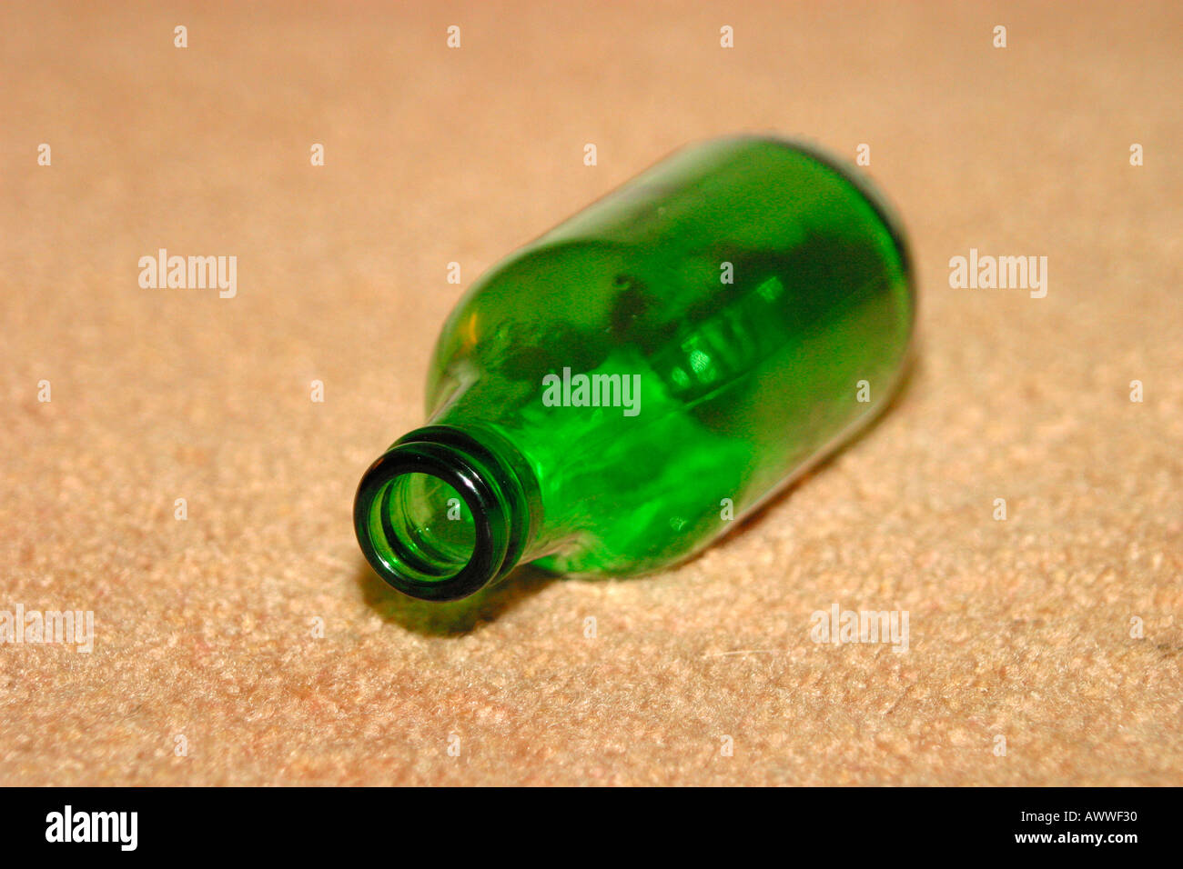 Empty beer bottle discarded on carpeted floor Stock Photo