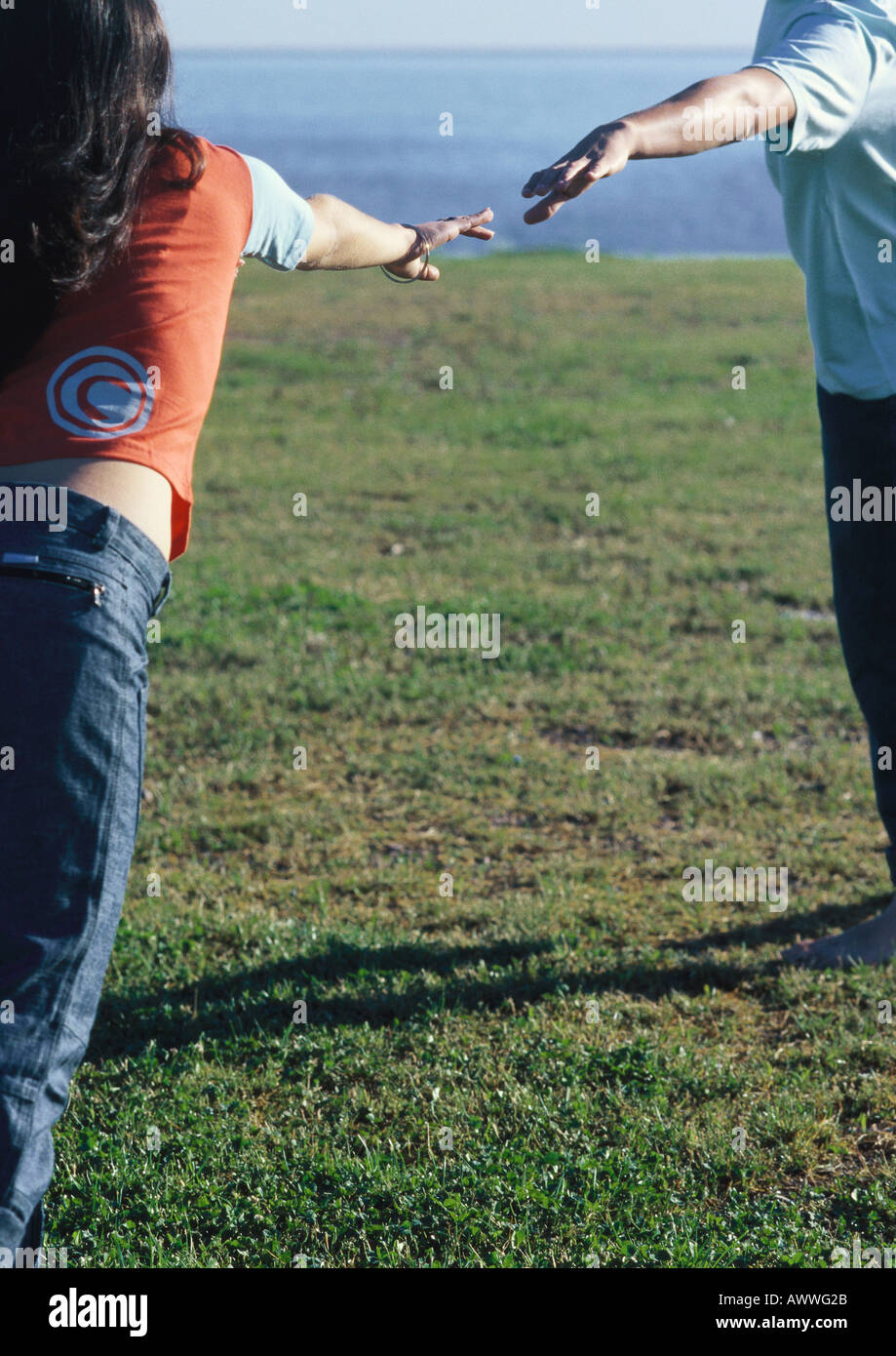 Young woman reaching, hurrying towards young man waiting with ams extended Stock Photo