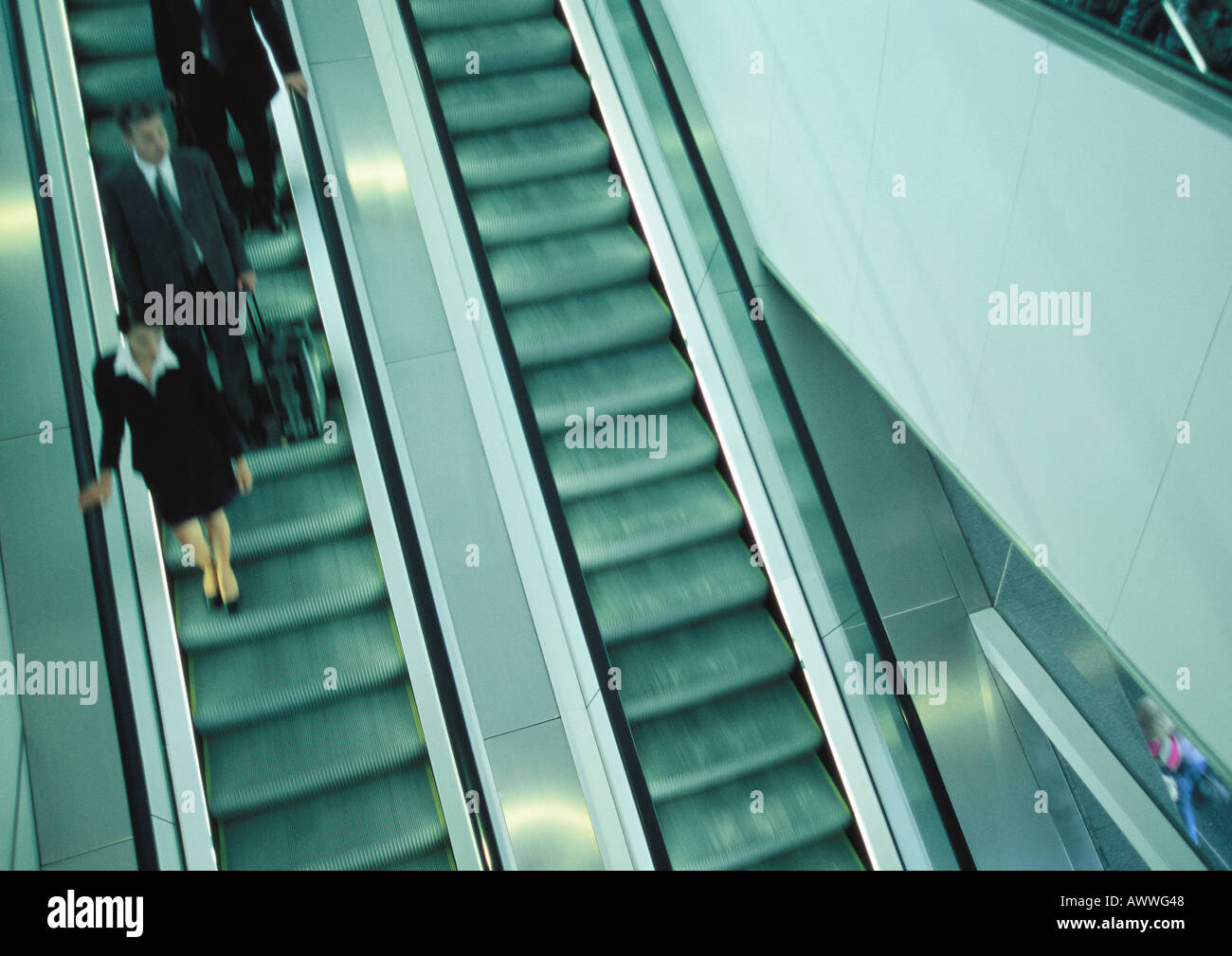 Business people on escalator going down, blurred, high angle view. Stock Photo