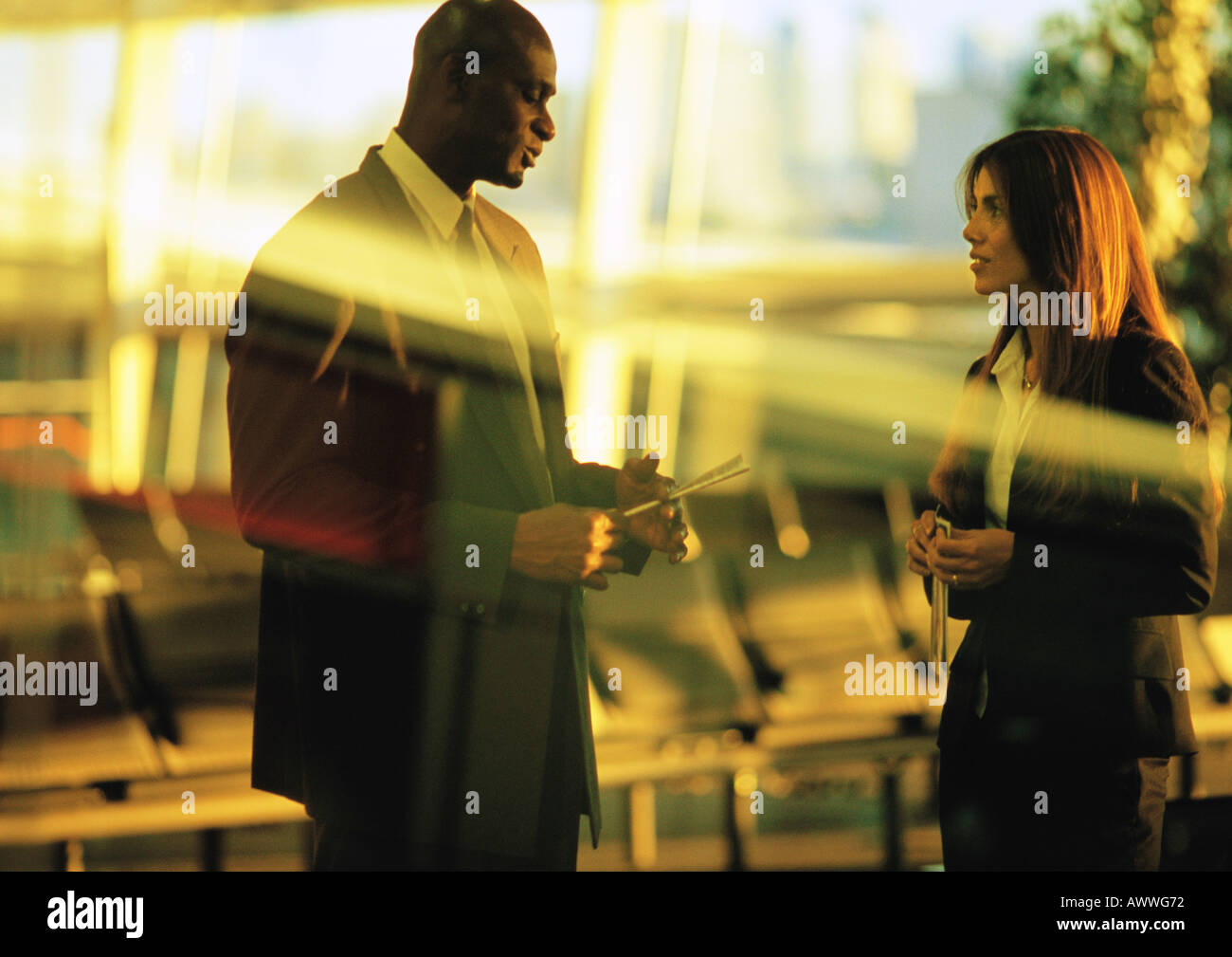 Businessman and businesswoman talking in airport terminal. Stock Photo