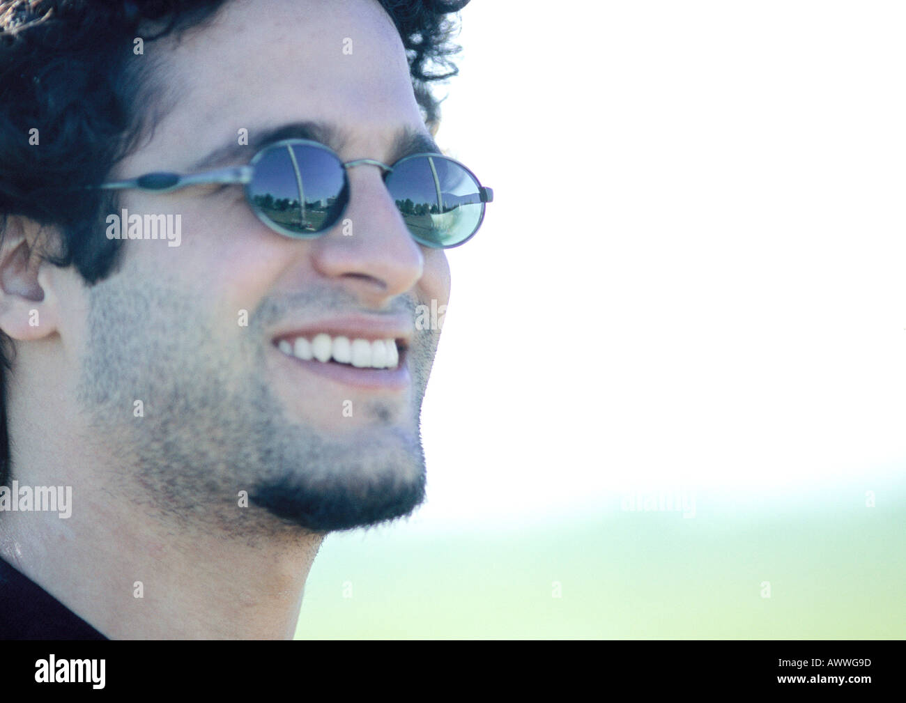 Man wearing sunglasses, smiling, side view, close-up Stock Photo