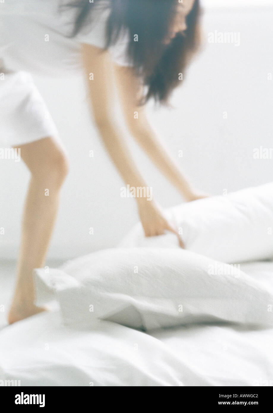 Woman bending over, picking up pillows, blurred Stock Photo