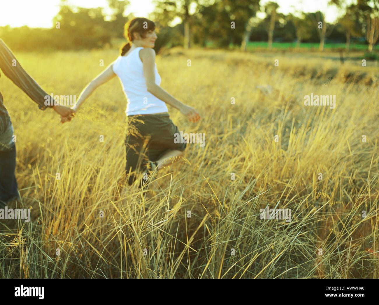 Couple walking in field of tall grass Stock Photo - Alamy