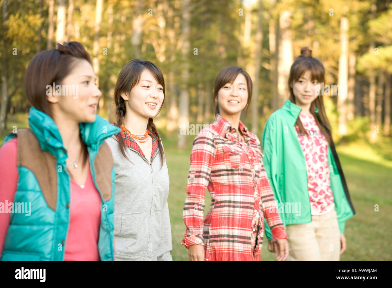 Four teenage girls walking side by side in forest, smiling Stock Photo ...
