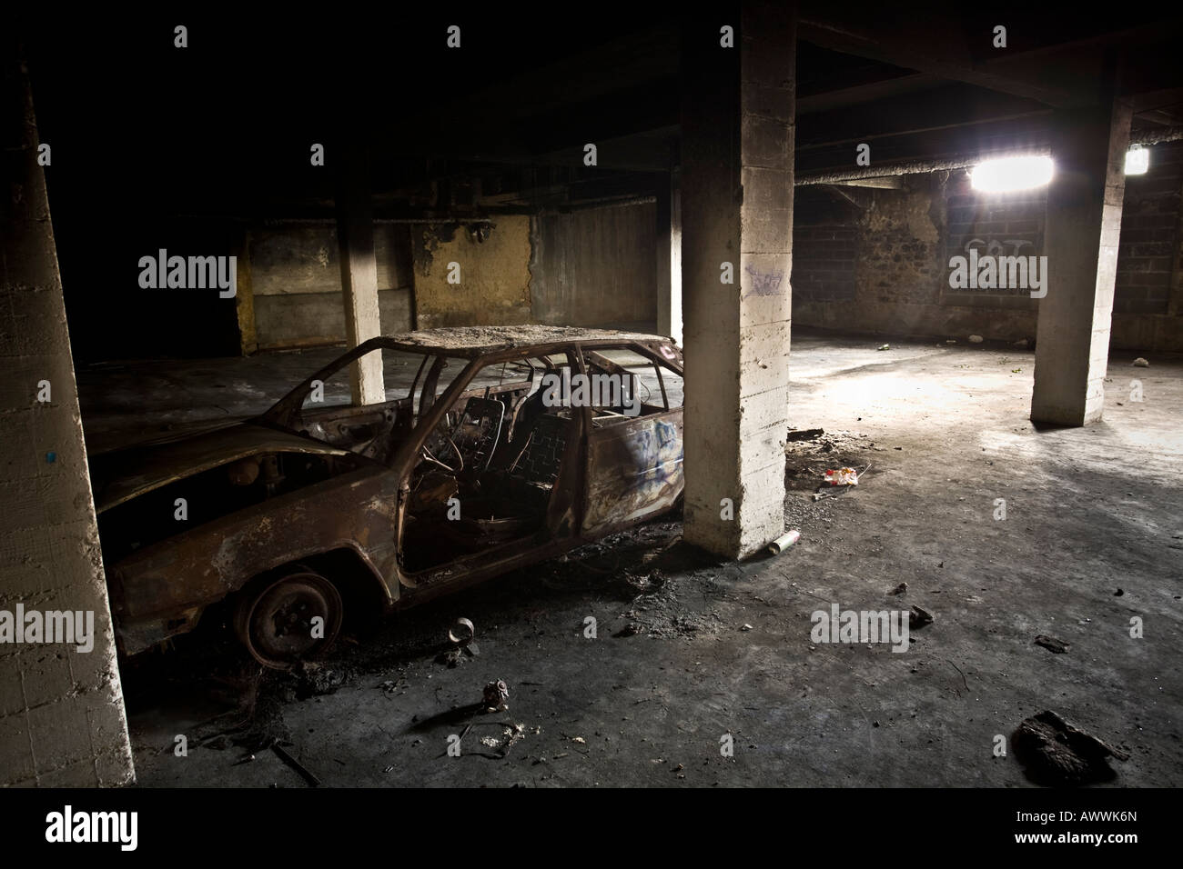 A burnt-out car abandoned in a council flats basement (France). Carcasse de voiture calcinée dans le sous-sol d'une HLM - France Stock Photo