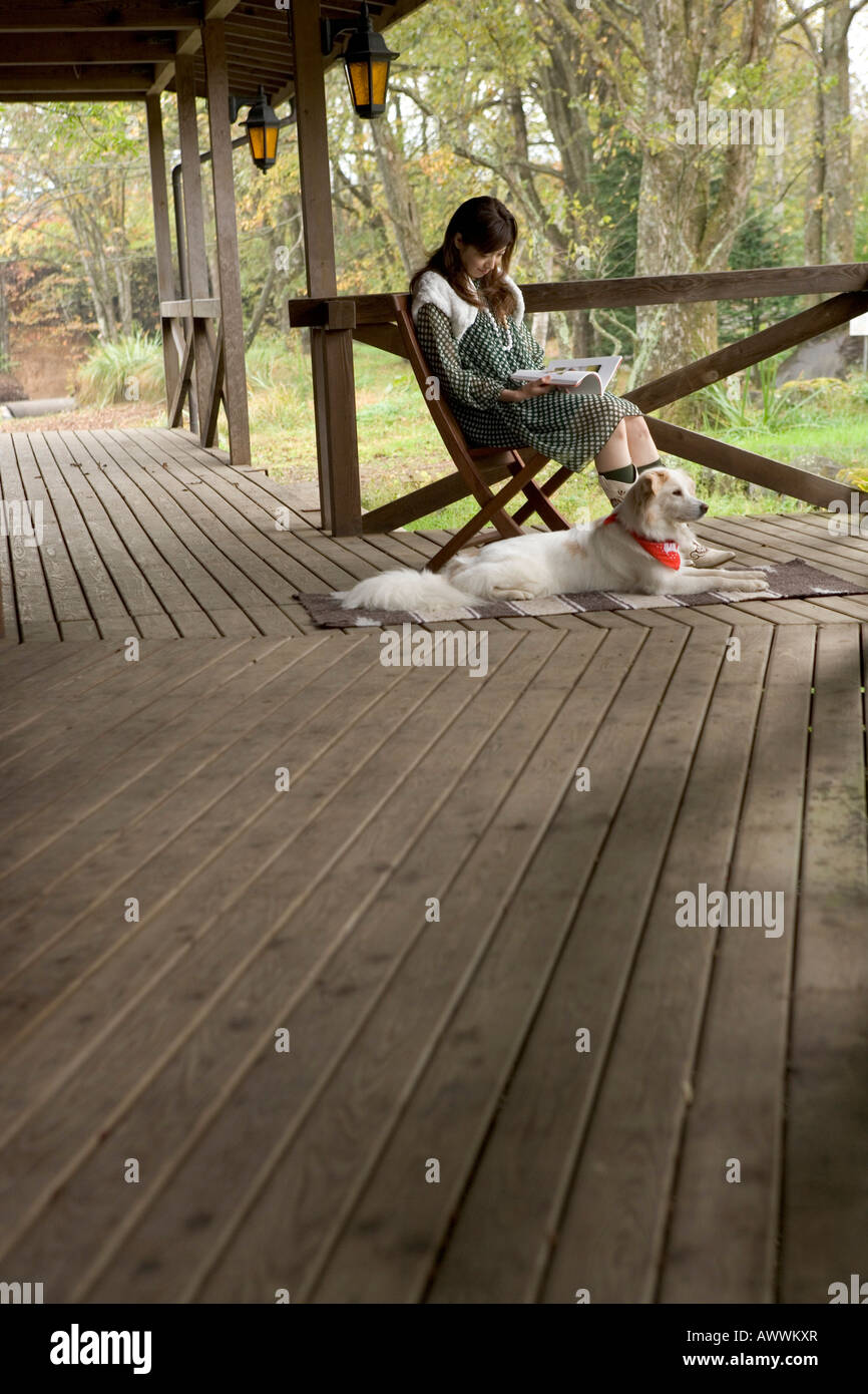 Young woman reading book on porch Stock Photo - Alamy