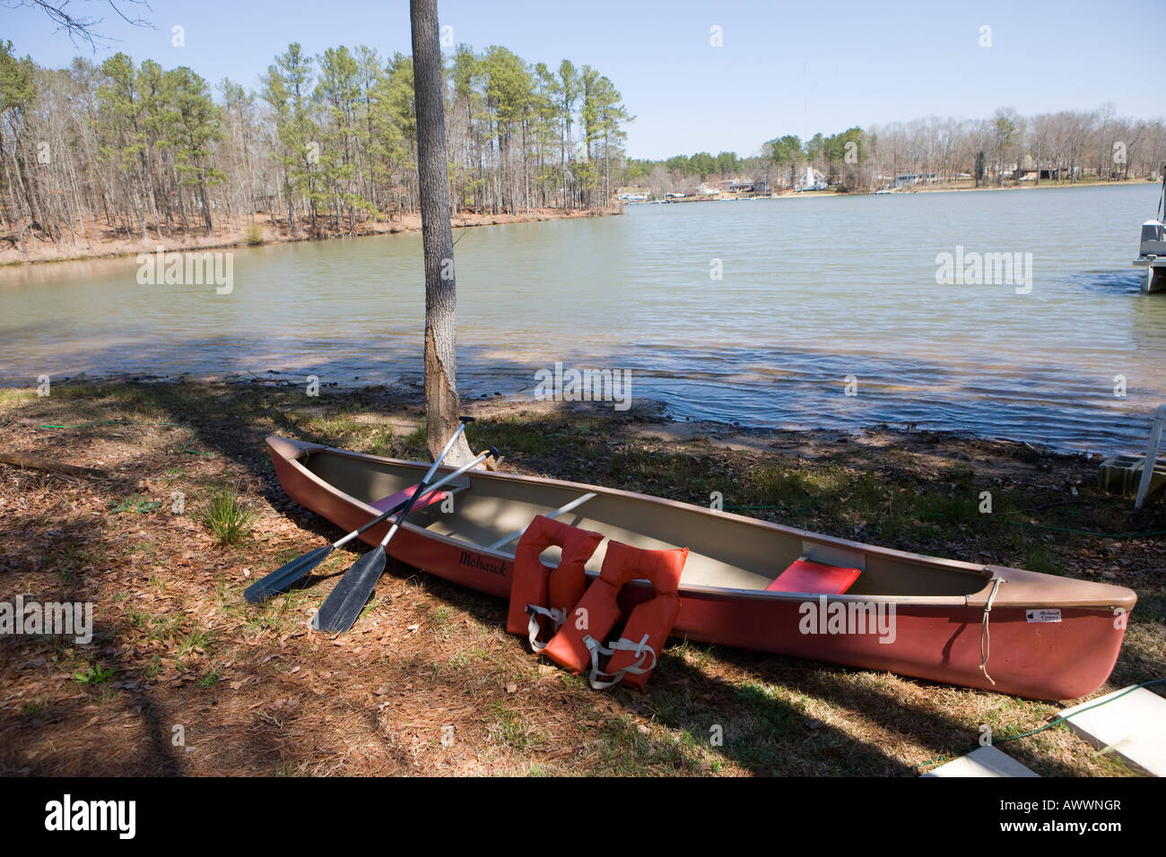 A canoe with two oars and life jackets sits along the shores of Lake Greenwood Cross Hill South Carolina, USA Stock Photo