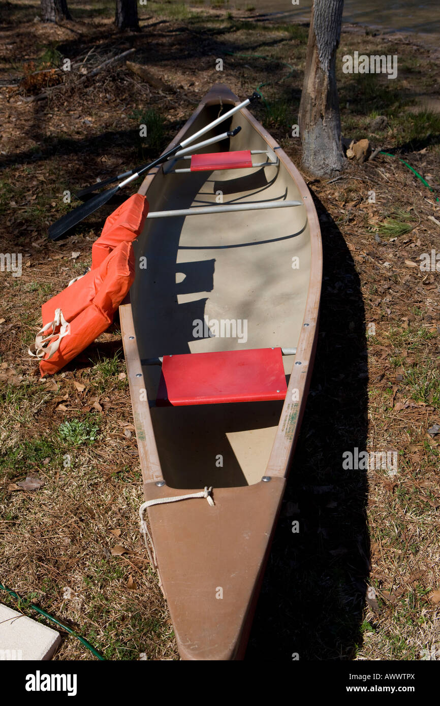 A canoe with two oars and life jackets sits along the shores of Lake Greenwood Cross Hill South Carolina, USA Stock Photo