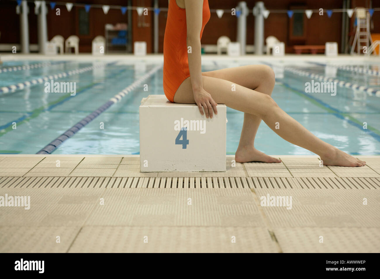 Female swimmer sitting on swimming starting block Stock Photo