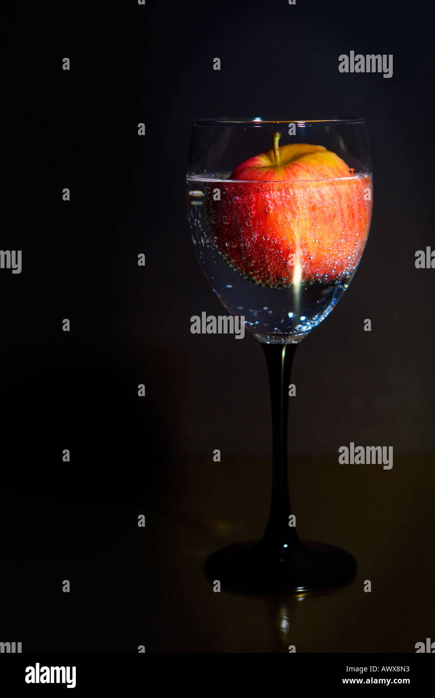 apple floating in bubbly seltzer water in black stem wine glass Stock Photo