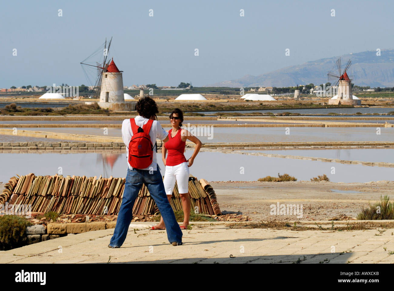 A couple taking a tourist picture among saline fields and windmills Mozia Island Sicily Italy Stock Photo