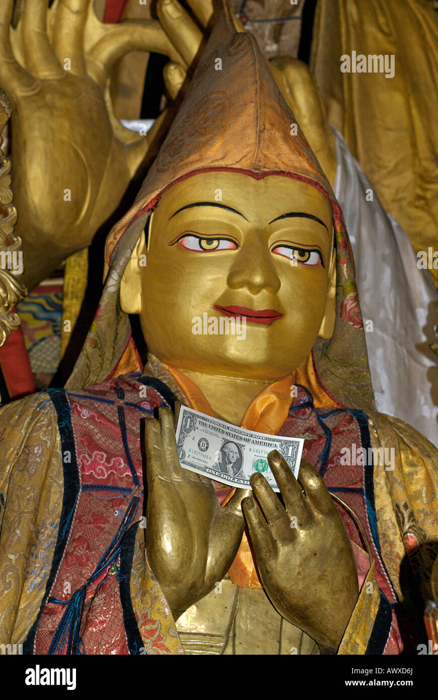 Dollar banknote in the hands of a buddhist statue of a previous Dalai Lama, Drepung, monastery, Lhasa, Tibet Stock Photo