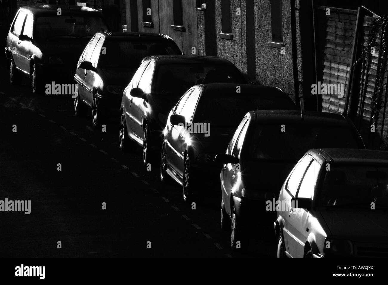 A line of parked cars reflect the early morning sun. Stock Photo