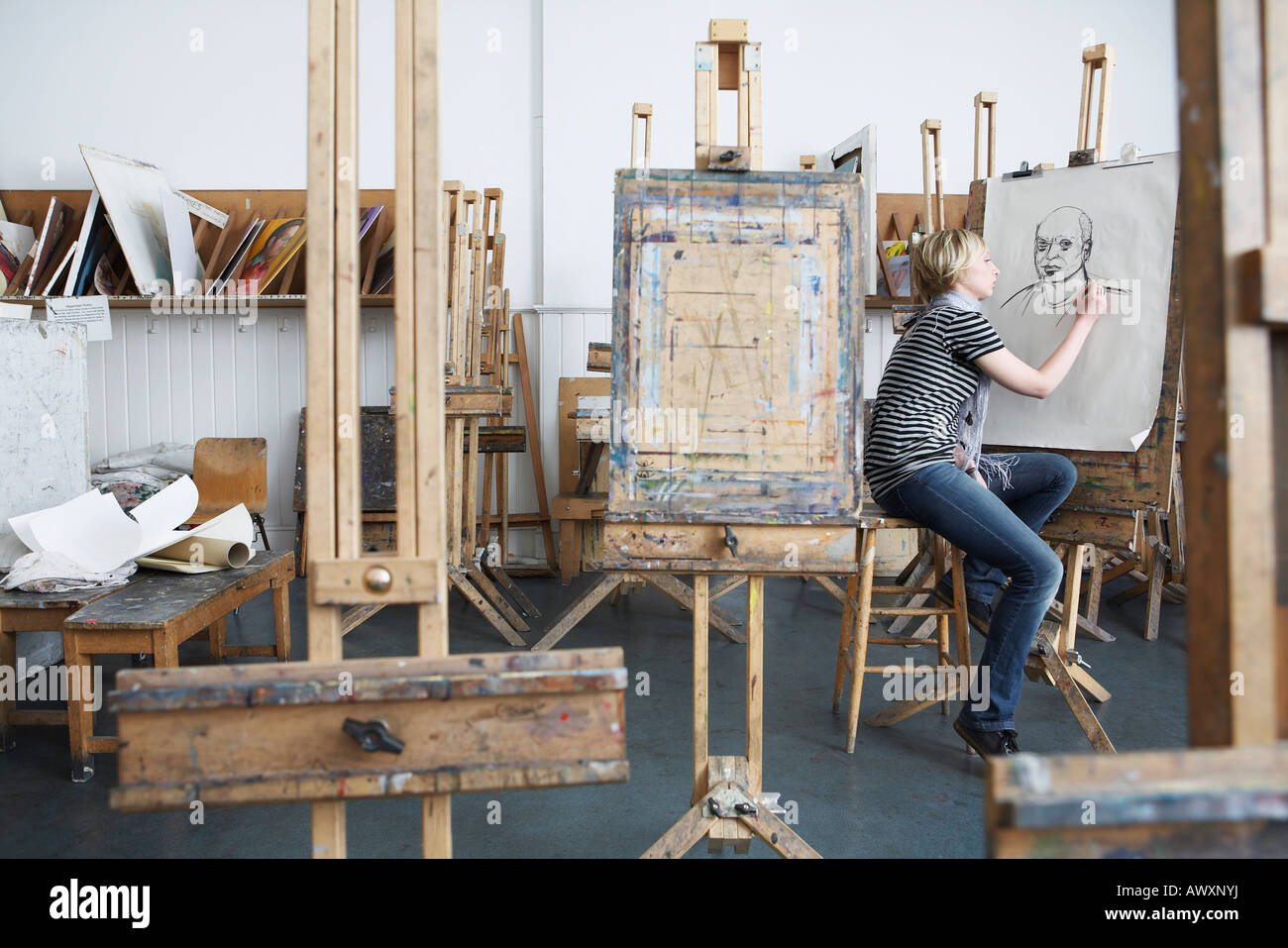Young female student drawing with charcoal in college art studio Stock