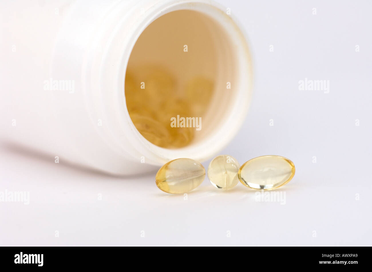 Clear liquid filled capsules spilling out of a bottle on its side Stock ...