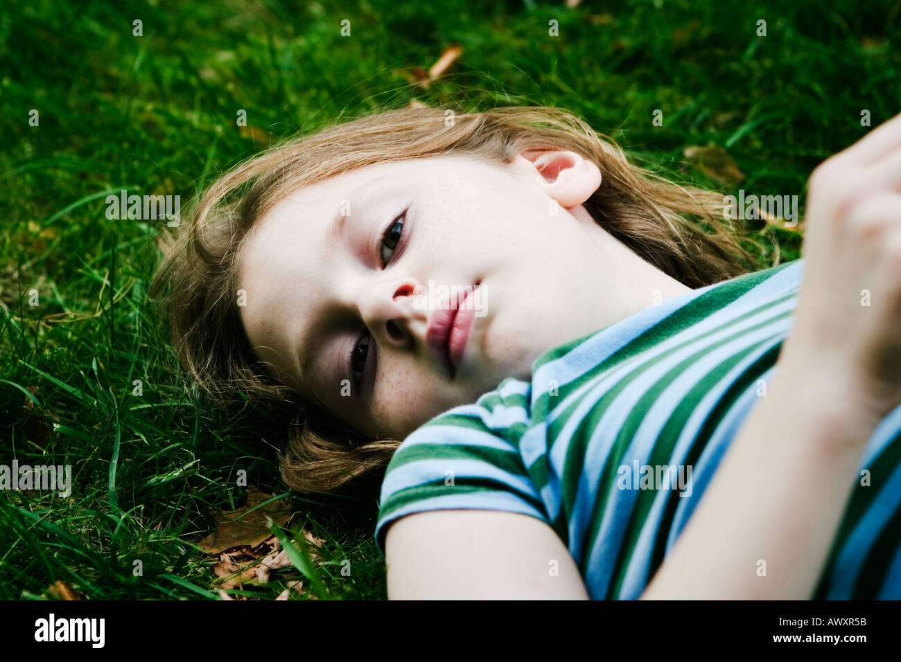 young girl laying in the grass on her back looking relaxed and calm enjoying a warm afternoon Stock Photo