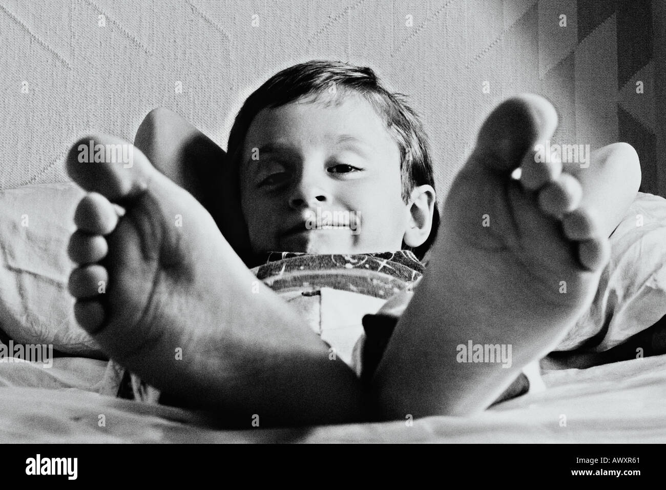 little-boy-lying-in-bed-with-big-giant-feet-stock-photo-alamy