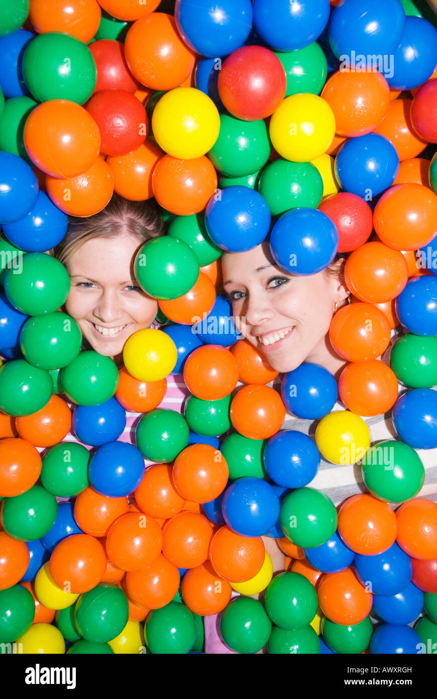 Two girls submerged in ball swamp at kids play area Stock Photo