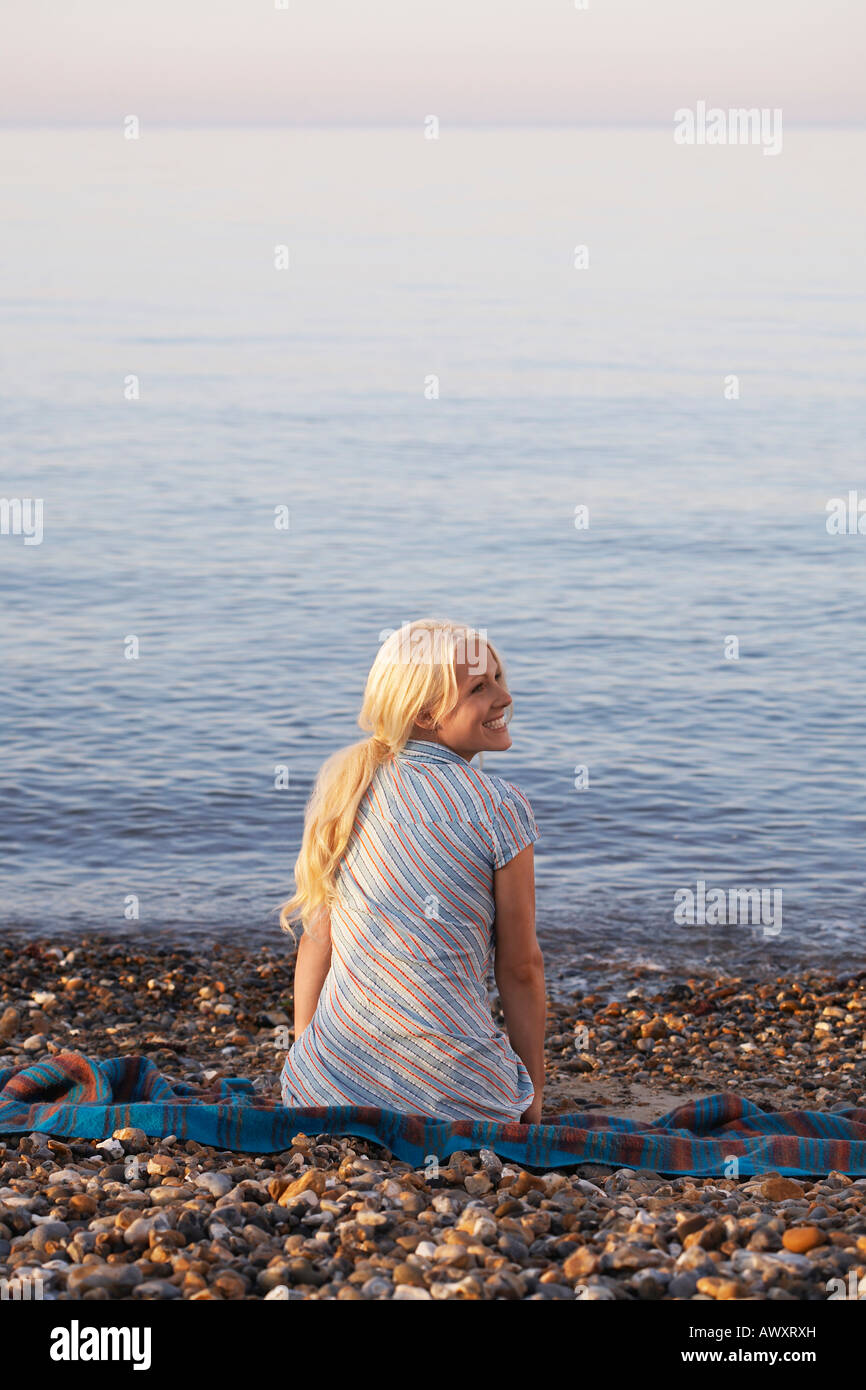 Young woman sitting on beach, back view Stock Photo - Alamy