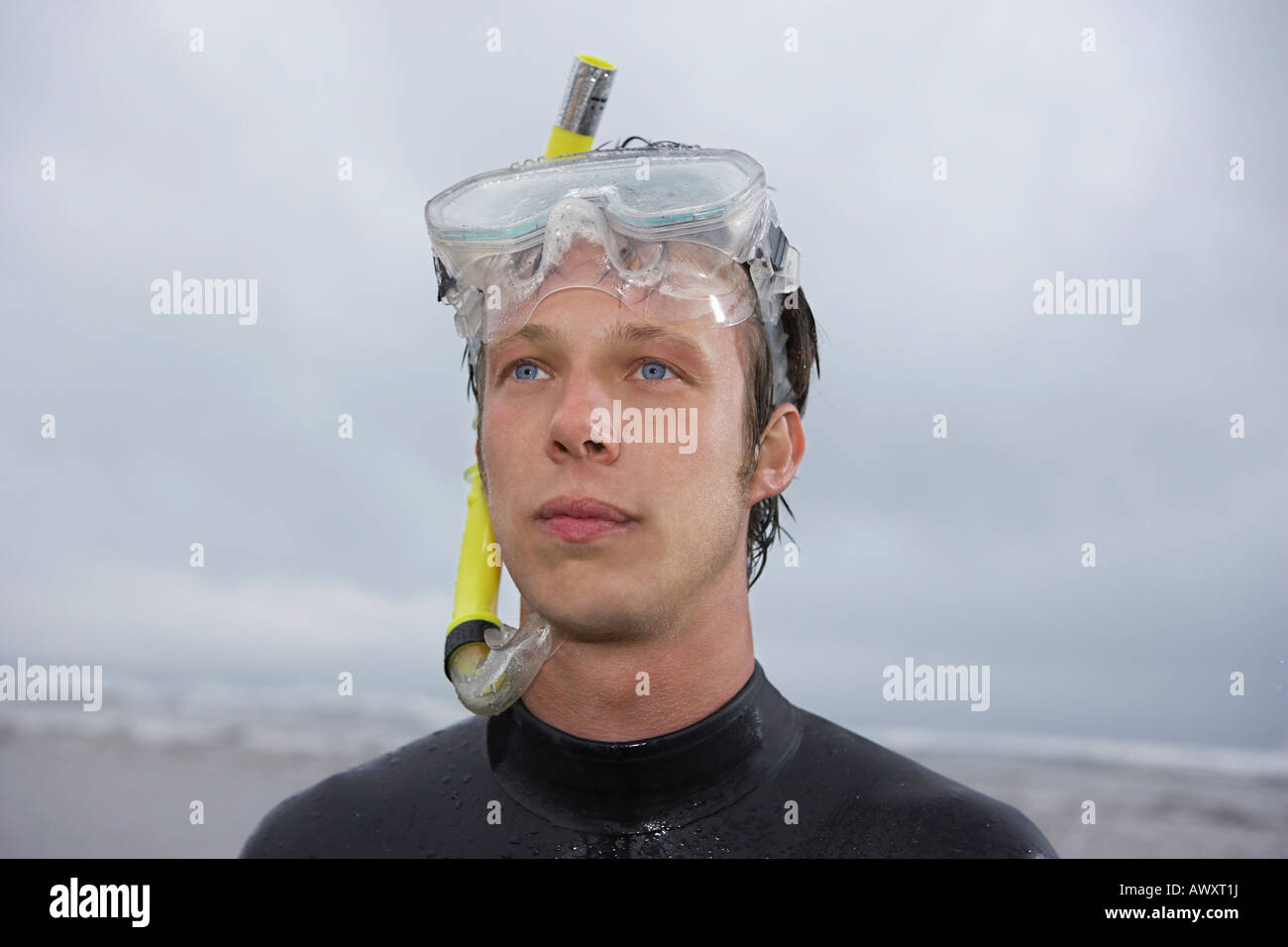 Man in wetsuit wearing snorkle, standing on beach, portrait Stock Photo