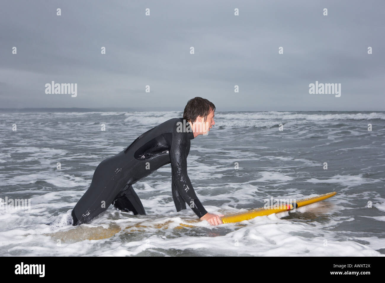 Surfer holding surfboard in water, side view Stock Photo