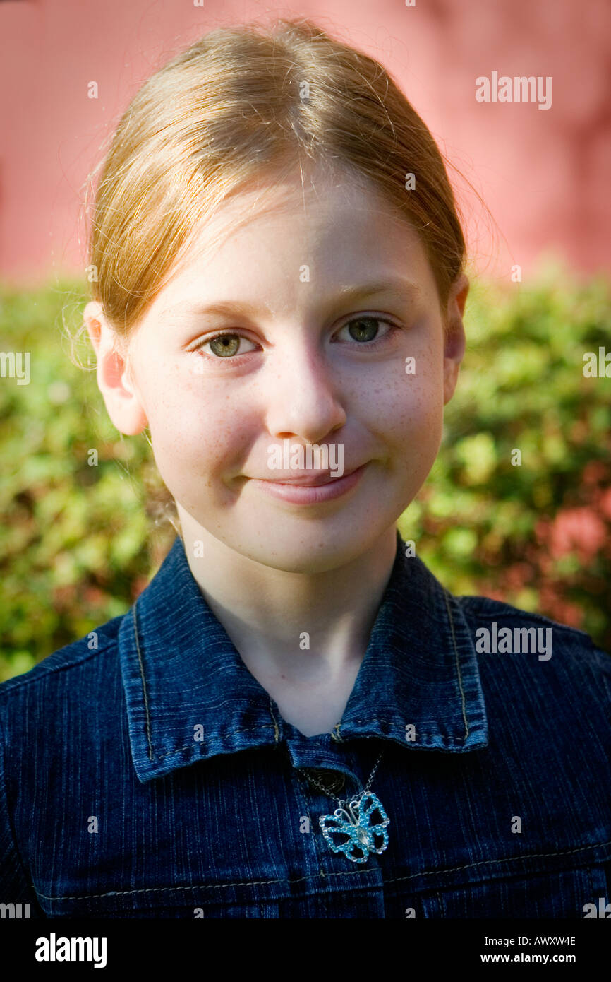 portrait of nine or ten year old girl in early morning sunlight outdoors  with hair pulled back smiling no teeth showing Stock Photo - Alamy