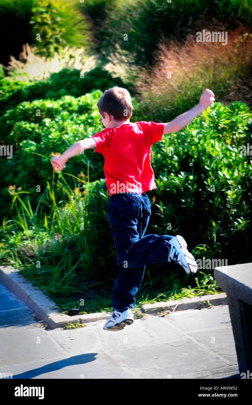 young boy running across a park bench then jumping off the end Stock Photo