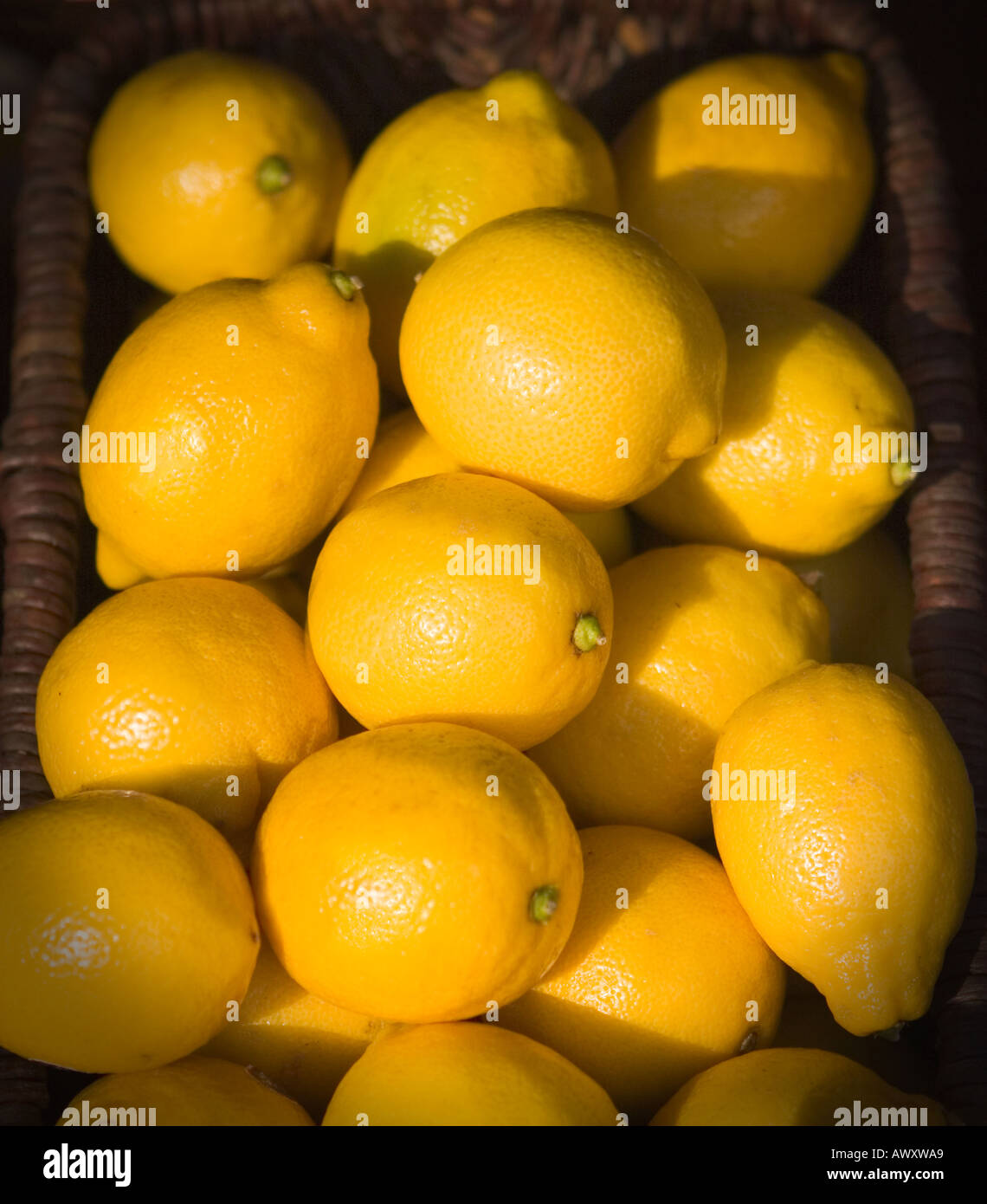 lemons in a wicker basket on display at a produce stand in an outdoor market Stock Photo