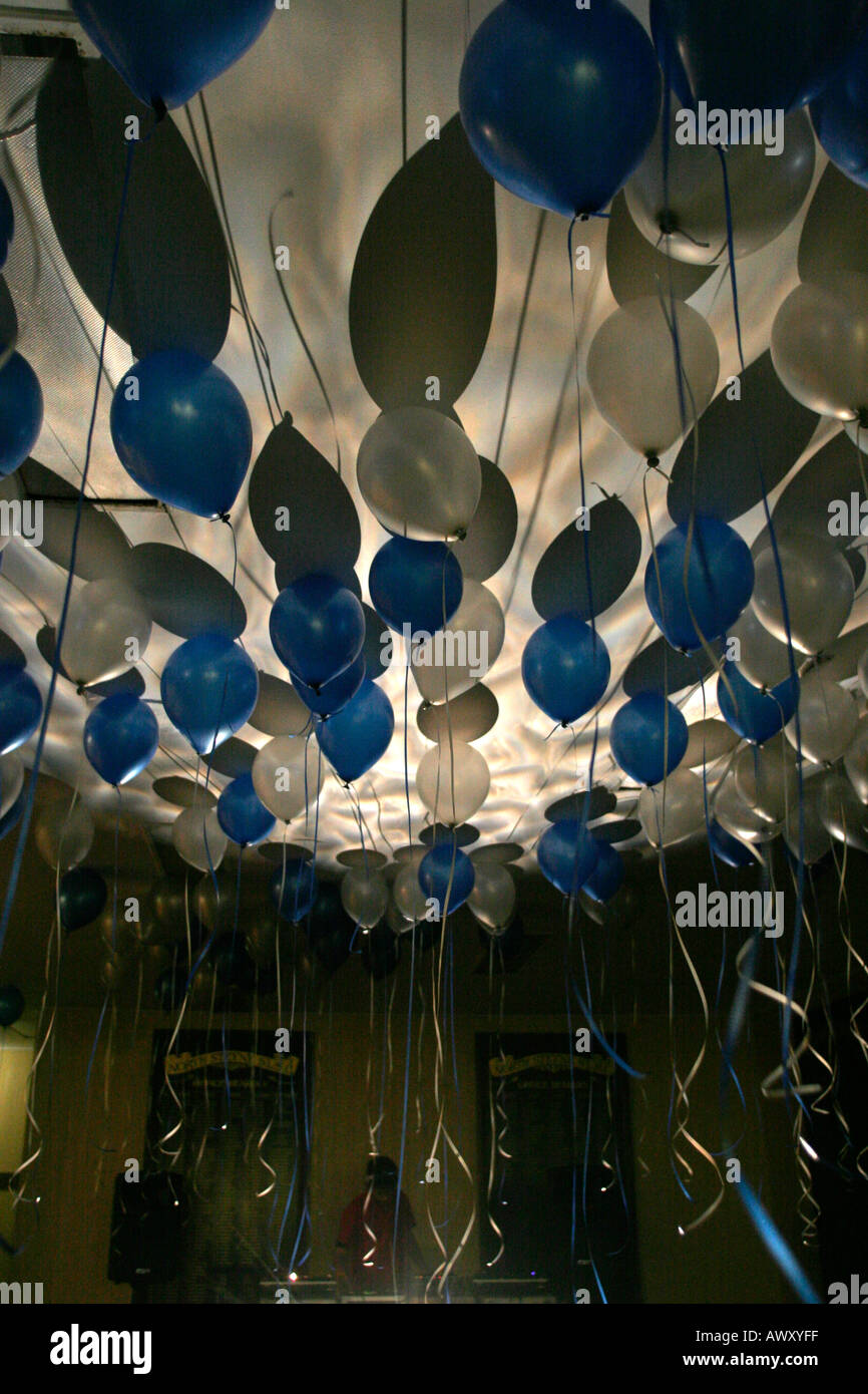 Helium filled party balloons float on the ceiling of a local hall where party is about to begin Stock Photo