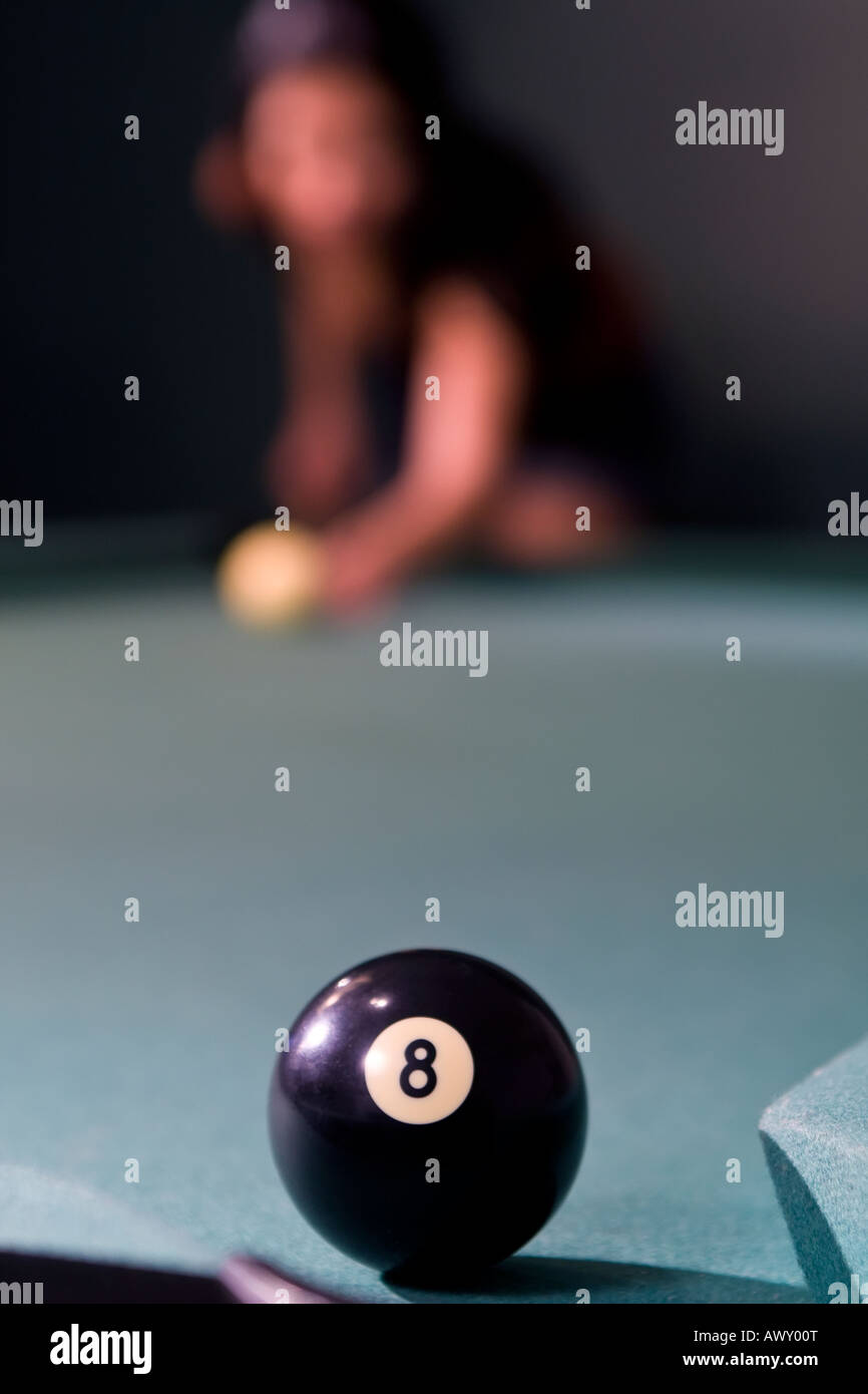 Selective focus shot of an eight ball over the pocket on a pool table