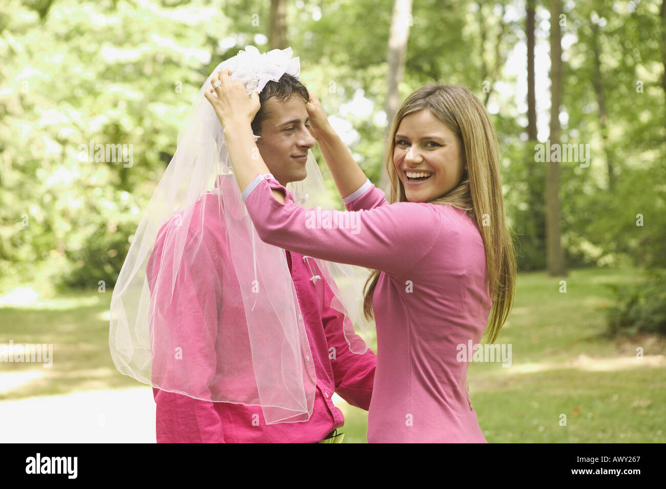Woman placing wedding veil on her husband Stock Photo