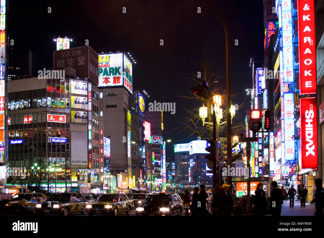 Busy street scene at night with many bright glowing signs on buildings along Yasukuni Dori in Shinjuku Tokyo Japan Stock Photo