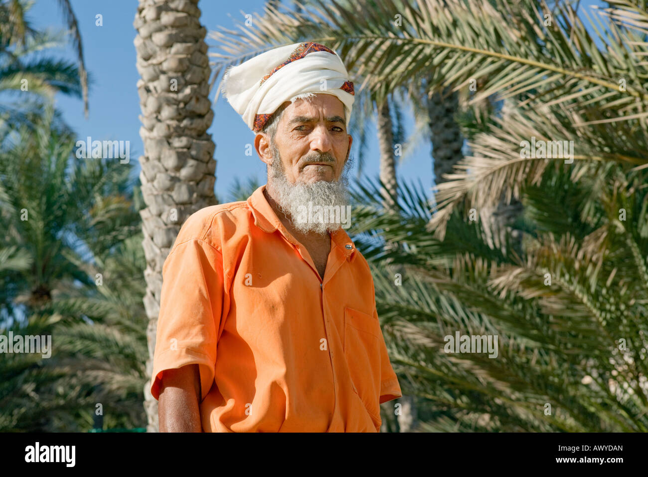 Village of Nakhl, Oman: Portrait of a bearded man wearing a white turban and orange jump suit Stock Photo