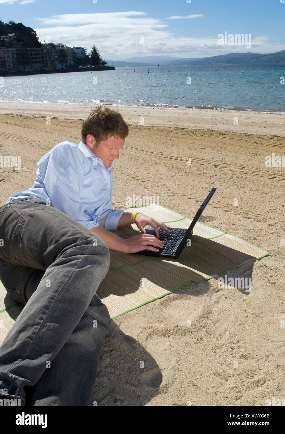 Young business man relaxing and using his computer at the beach on a ...