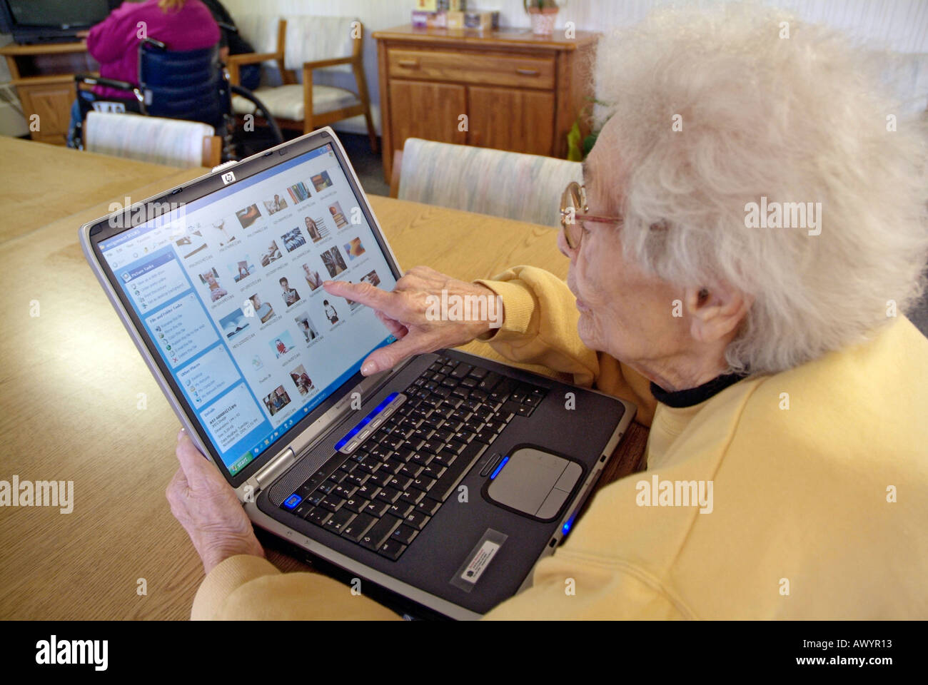 Handicapped Senior female in a wheelchair in a nursing home checks email on a wireless internet connection on a laptop computer Stock Photo