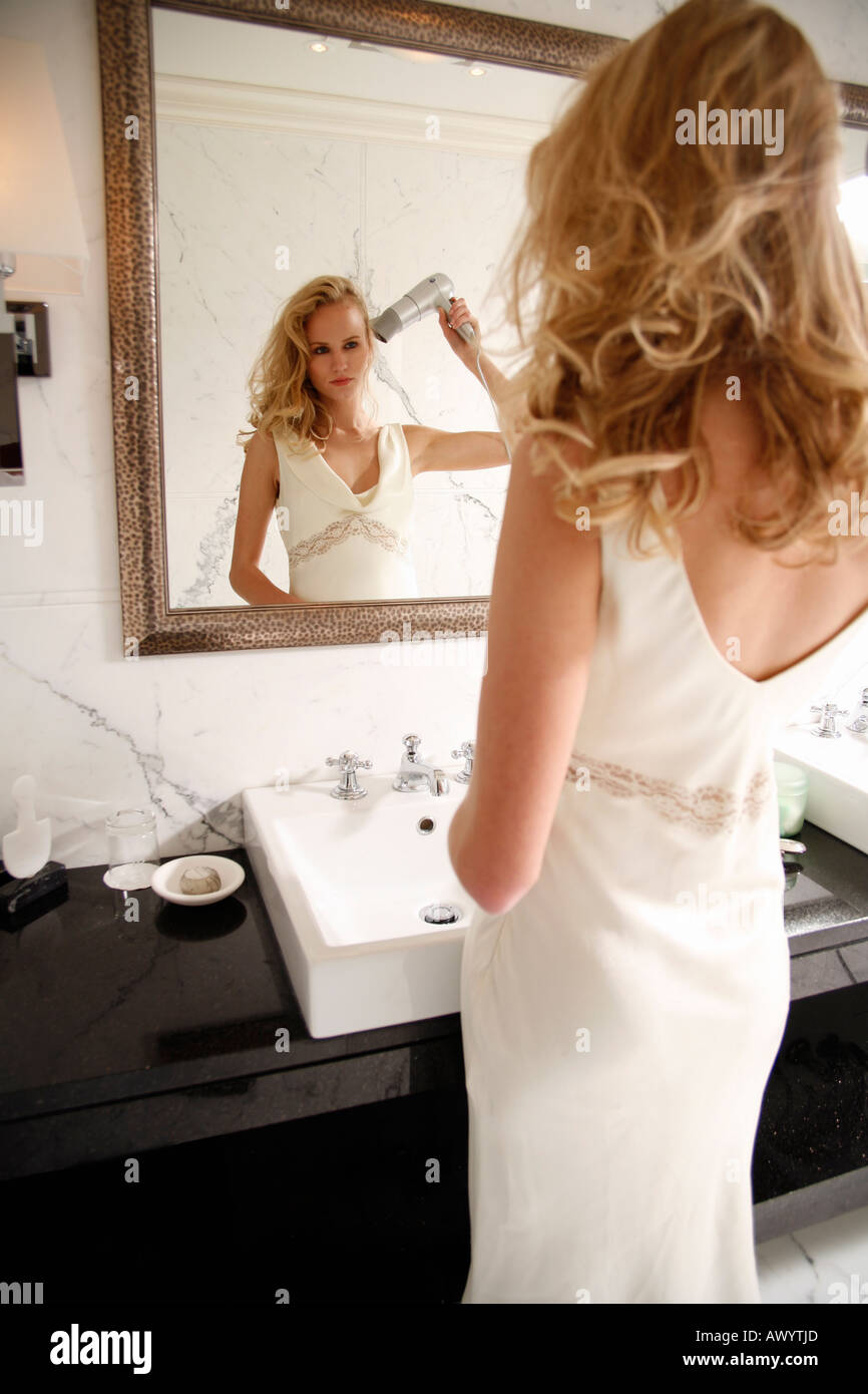 Woman drying her hair in bathroom Stock Photo
