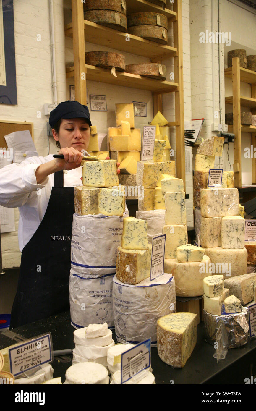 A worker at Neals Yard Dairy in Borough Market, London UK, slices cheese for customers. Stock Photo