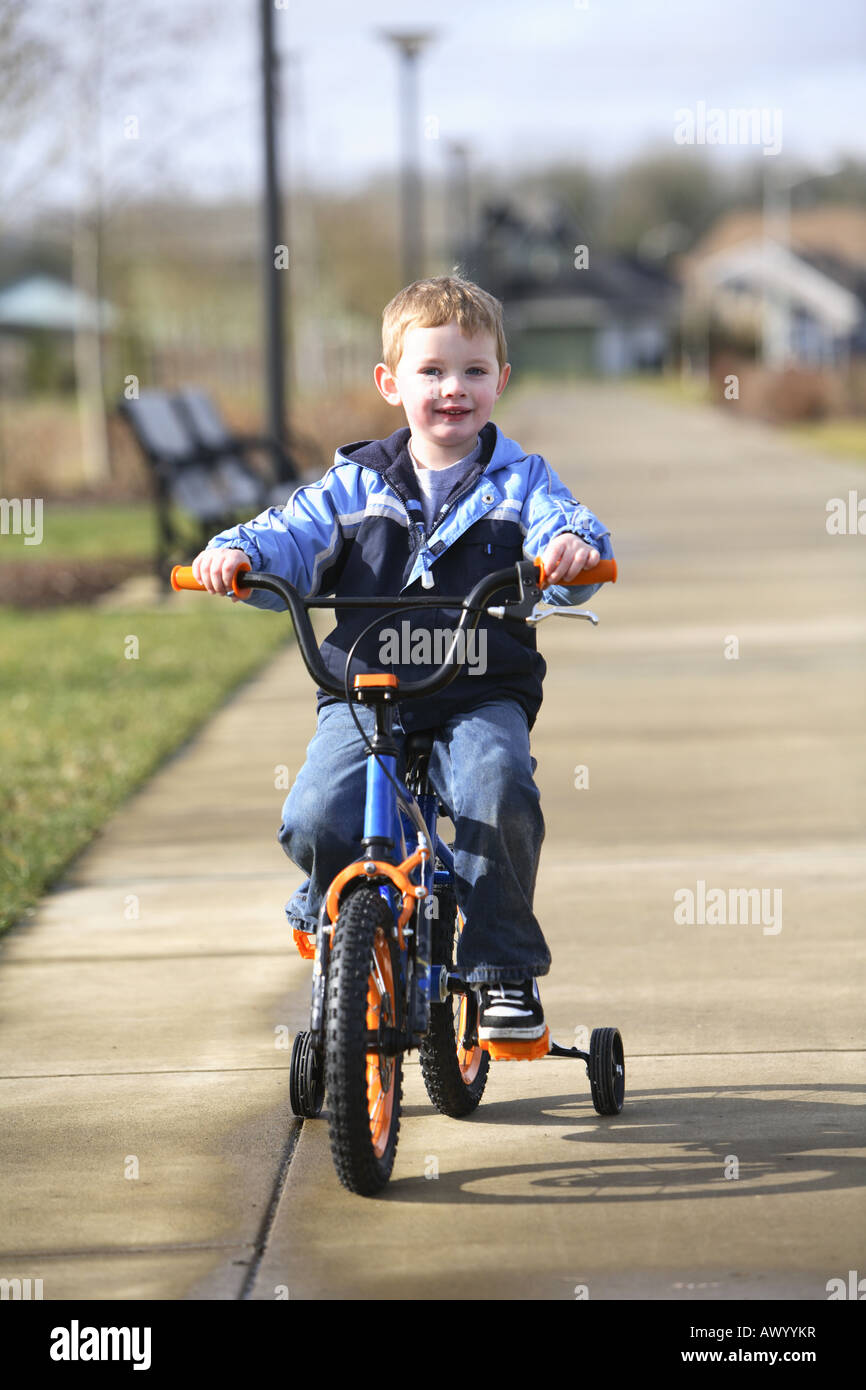 Young boy riding bicycle with training wheels Stock Photo Alamy