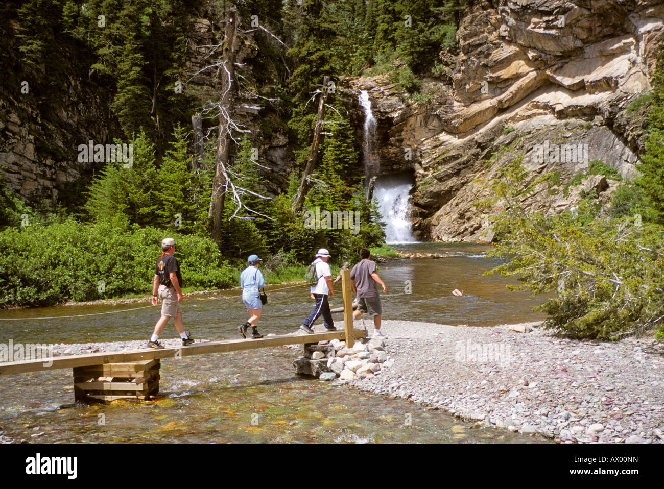 Family walks across forestry bridge to visit water falls in Montana USA Stock Photo