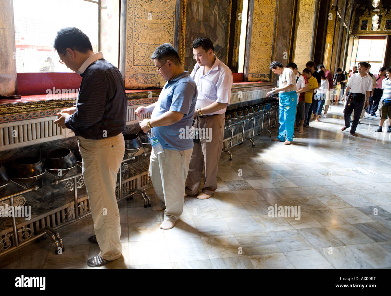 People Dropping Coins Into The Alms Meditation Collection Bowls Wat Po Thailand South East Asia Stock Photo