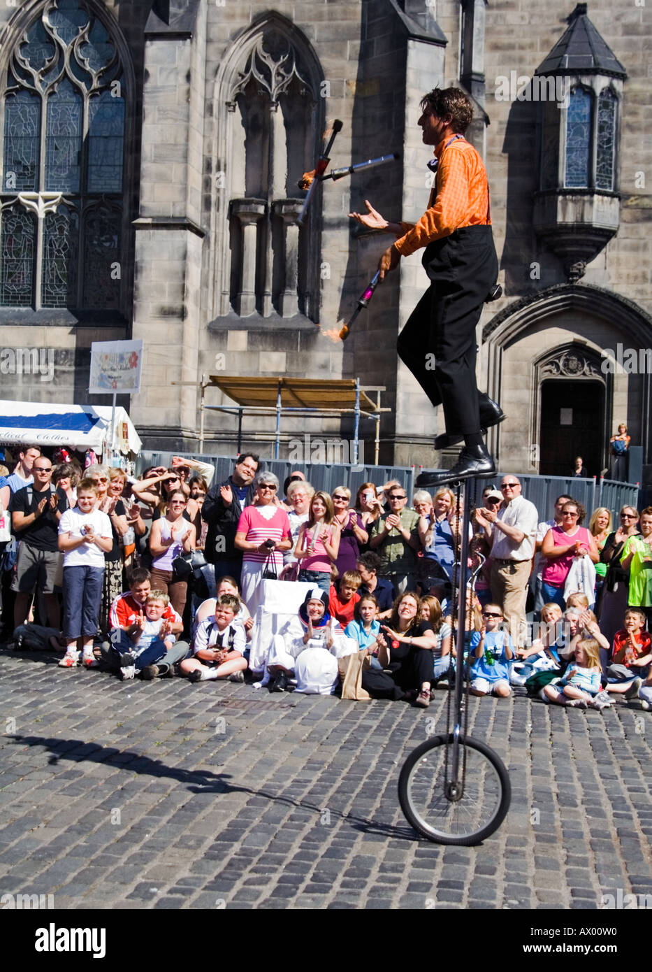 Street entertainer on a unicycle juggling fire clubs at the Edinburgh